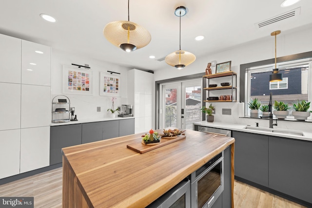 kitchen featuring gray cabinets, visible vents, a sink, and wood counters