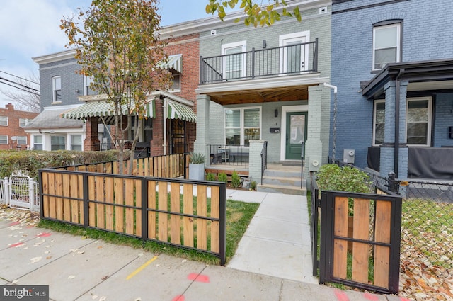 multi unit property with covered porch, brick siding, a fenced front yard, and a gate