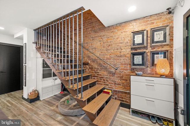 stairway featuring recessed lighting, brick wall, and wood finished floors