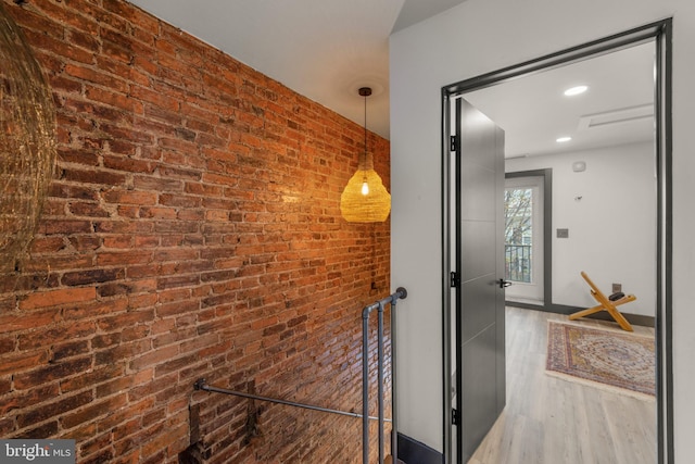 hallway with recessed lighting, brick wall, and wood finished floors