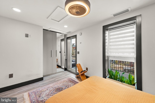 bedroom featuring visible vents, attic access, light wood-style flooring, and multiple windows