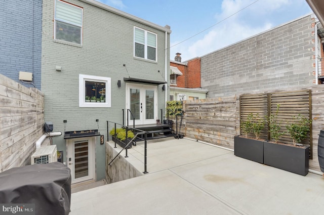back of property with french doors, a fenced backyard, a patio area, and brick siding