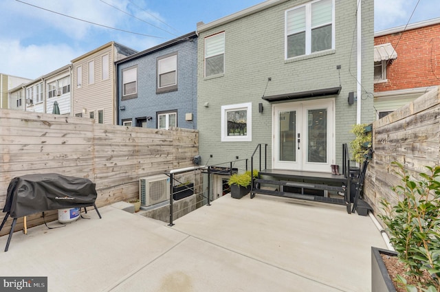 rear view of house featuring brick siding, ac unit, french doors, and a patio
