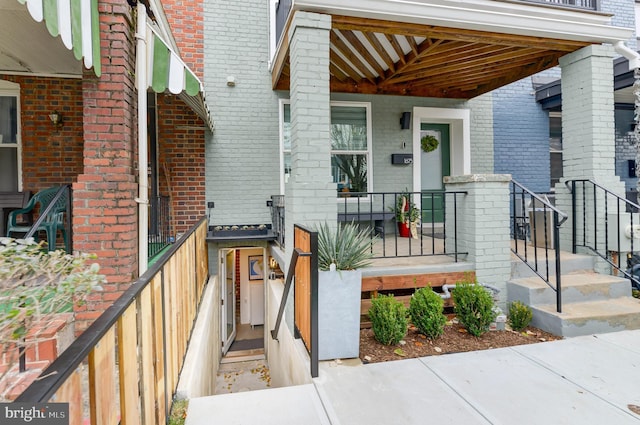 entrance to property with a porch and brick siding