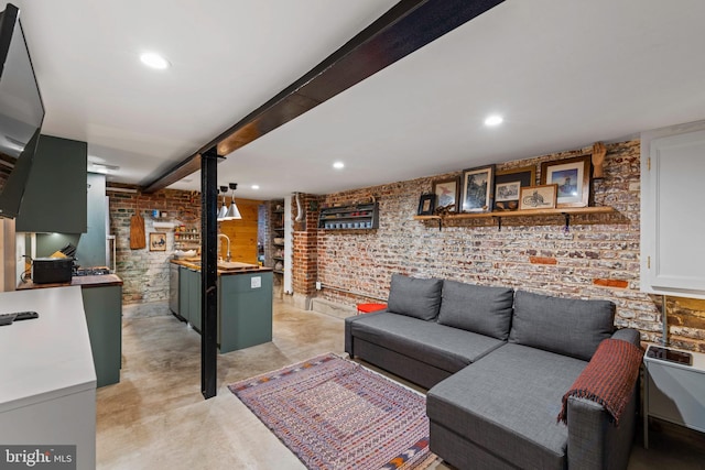 living room featuring brick wall, concrete flooring, recessed lighting, and beam ceiling