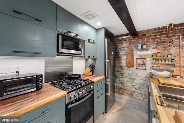 kitchen with visible vents, butcher block counters, a toaster, concrete floors, and appliances with stainless steel finishes