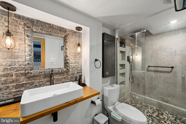 bathroom featuring a sink, tasteful backsplash, a stall shower, and toilet