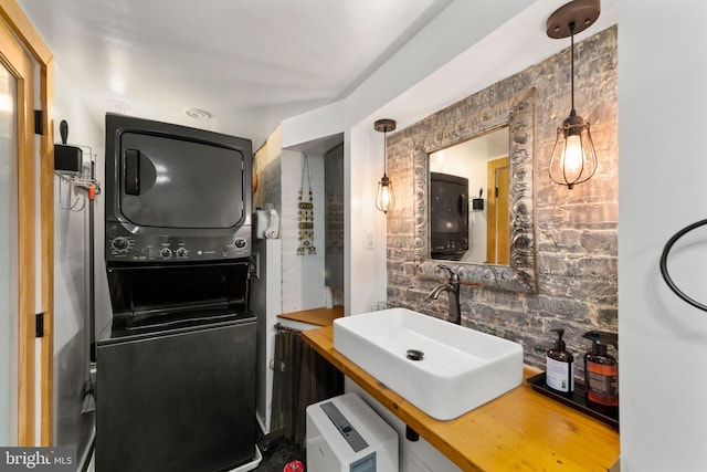 bathroom with a sink, stacked washer / dryer, and tasteful backsplash