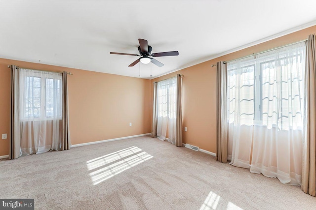 empty room with a ceiling fan, visible vents, light carpet, and baseboards