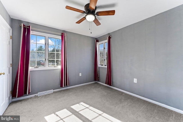 unfurnished room with ceiling fan, carpet, visible vents, and baseboards