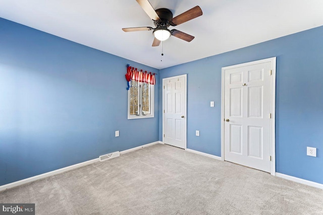 unfurnished bedroom featuring ceiling fan, carpet floors, visible vents, and baseboards