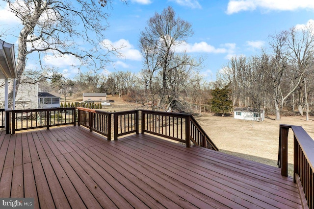 wooden deck with an outdoor structure, a lawn, and a storage unit