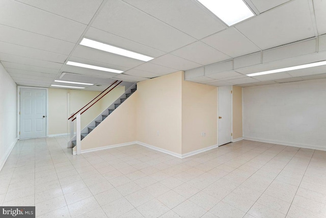 finished below grade area with baseboards, stairway, and a drop ceiling