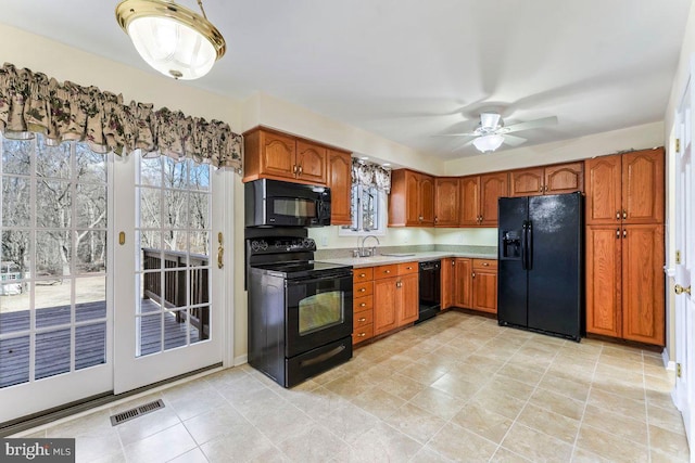 kitchen featuring a ceiling fan, visible vents, light countertops, brown cabinets, and black appliances