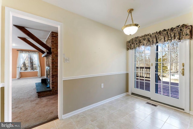 unfurnished dining area featuring carpet floors, a fireplace, visible vents, tile patterned flooring, and baseboards