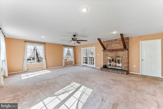 unfurnished living room with a ceiling fan, carpet flooring, a fireplace, and baseboards