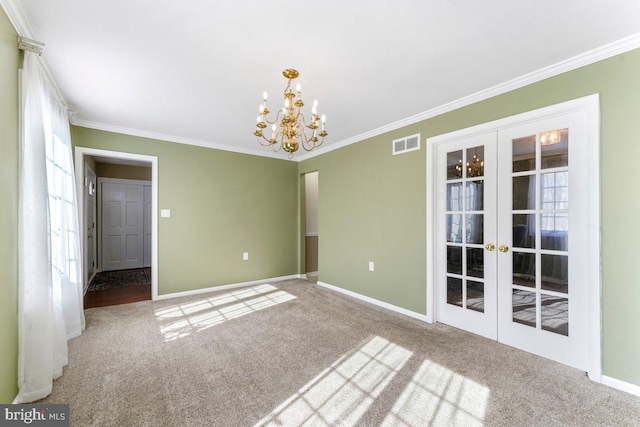 carpeted spare room featuring a notable chandelier, visible vents, baseboards, ornamental molding, and french doors