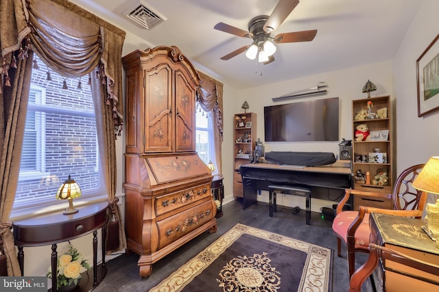 living area with dark wood-style floors, visible vents, and a ceiling fan