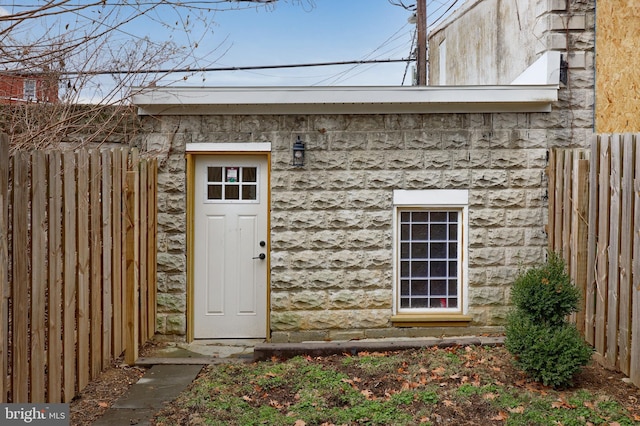 entrance to property with stone siding and fence