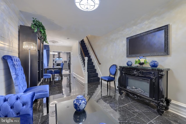 living area featuring marble finish floor, stairway, a fireplace, and baseboards