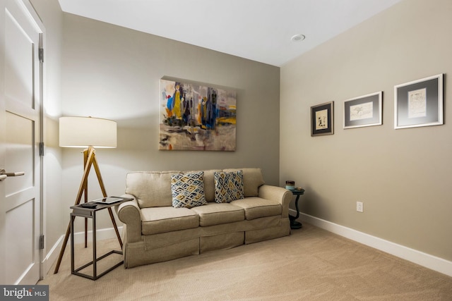 living area featuring light carpet and baseboards