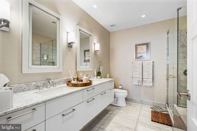 full bath with visible vents, toilet, vanity, tiled shower, and baseboards