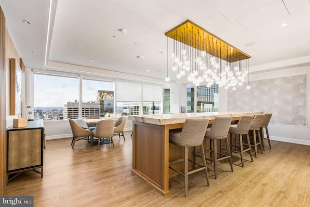 kitchen with a center island, decorative light fixtures, light countertops, light wood-style flooring, and baseboards