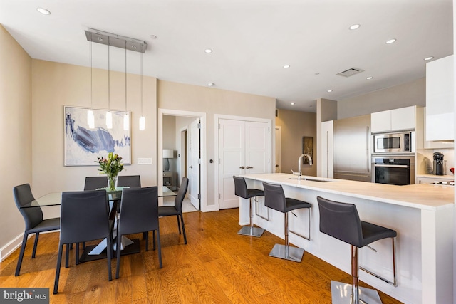 kitchen featuring decorative light fixtures, light countertops, appliances with stainless steel finishes, white cabinetry, and modern cabinets