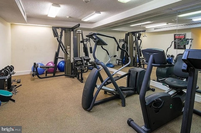 exercise room featuring a textured ceiling and baseboards