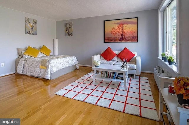 bedroom featuring a textured ceiling, wood finished floors, and baseboards