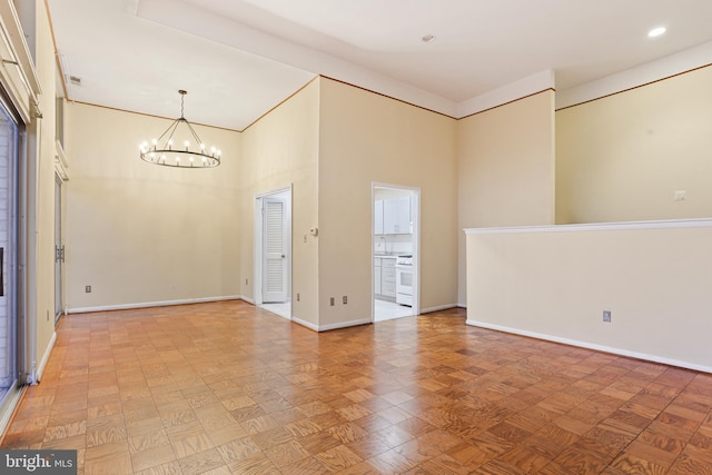 unfurnished room with a high ceiling, a notable chandelier, and baseboards