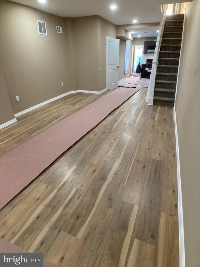 below grade area with visible vents, stairway, baseboards, and hardwood / wood-style flooring