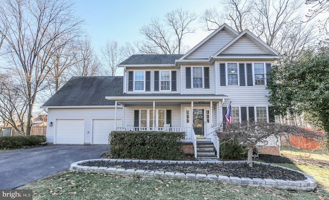 view of front of house featuring driveway, a shingled roof, a garage, and a porch