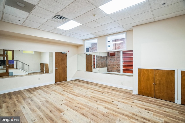 spare room with baseboards, visible vents, a drop ceiling, wood finished floors, and stairs