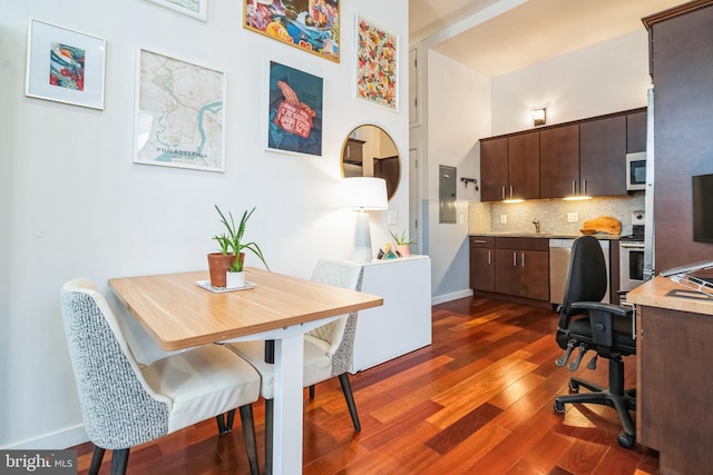 interior space featuring dark wood-type flooring, a towering ceiling, electric panel, and baseboards