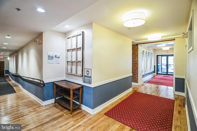 corridor featuring french doors, baseboards, and wood finished floors