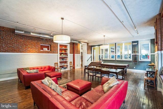 living room featuring brick wall, track lighting, baseboards, and hardwood / wood-style floors