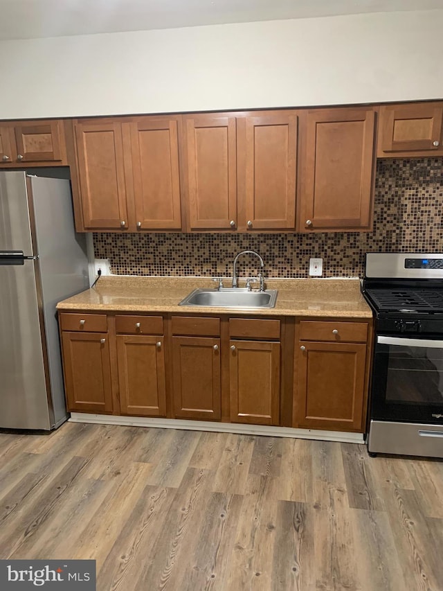 kitchen with stainless steel appliances, light wood-style floors, light countertops, and a sink