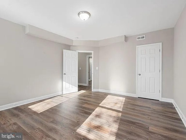 spare room with baseboards, visible vents, and dark wood-type flooring