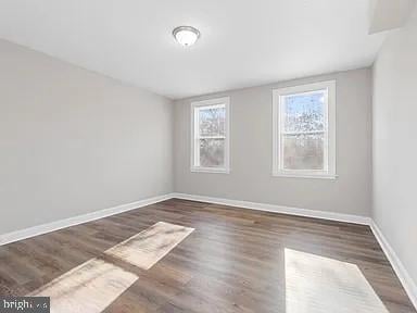 unfurnished room featuring dark wood-style flooring and baseboards