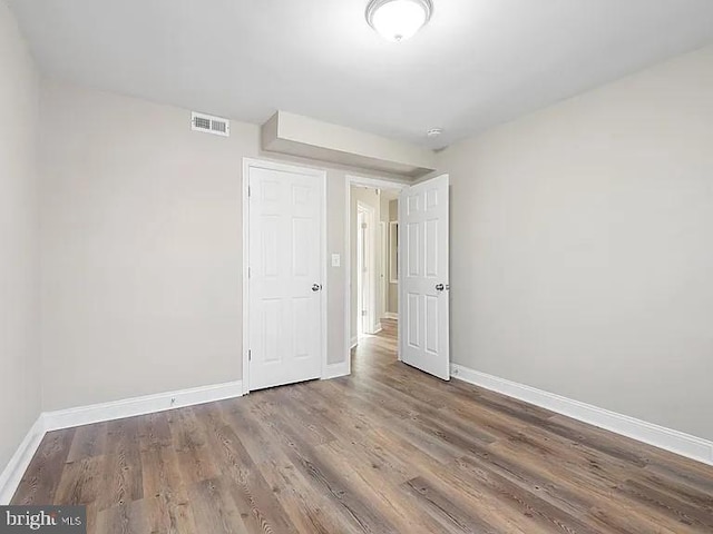 spare room with wood finished floors, visible vents, and baseboards