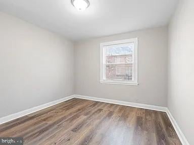 empty room featuring dark wood-type flooring and baseboards