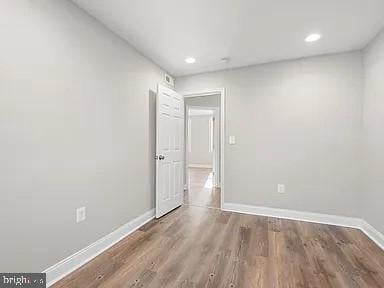 empty room featuring recessed lighting, dark wood finished floors, and baseboards