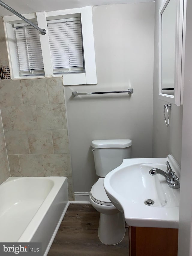 full bath featuring shower / bathtub combination, toilet, vanity, wood finished floors, and baseboards