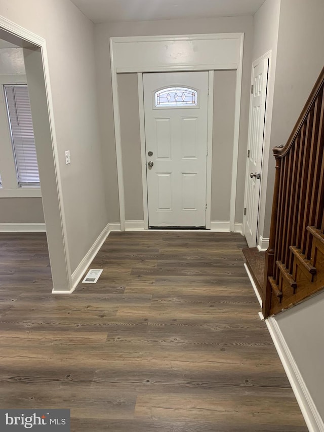 foyer entrance featuring dark wood-style floors, visible vents, and baseboards