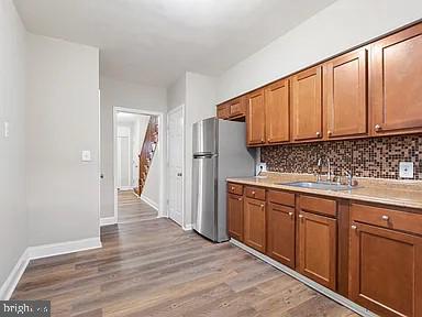 kitchen with brown cabinetry, light countertops, a sink, and tasteful backsplash