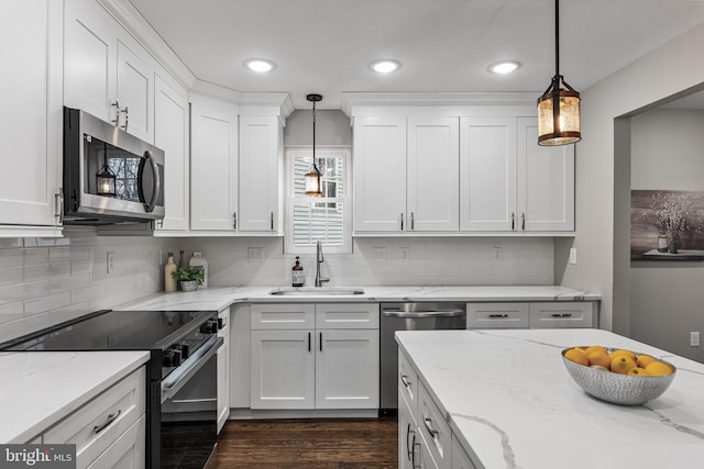 kitchen with stainless steel appliances, decorative light fixtures, a sink, and white cabinetry