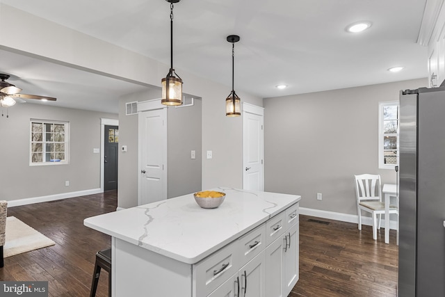 kitchen featuring decorative light fixtures, a kitchen island, freestanding refrigerator, and white cabinetry