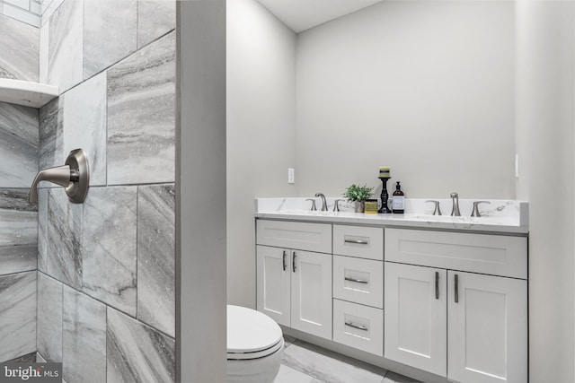 bathroom featuring marble finish floor, a sink, toilet, and double vanity