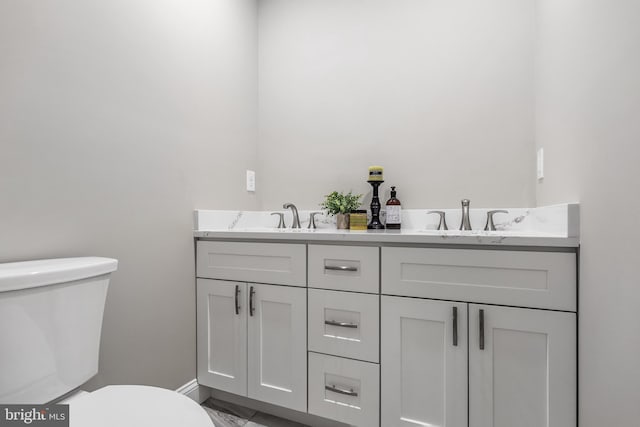 bathroom with a sink, toilet, and double vanity